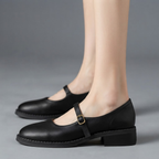 Britt Mary-Jane Flats Block-Heel in Black featuring a classic closed-toe design, adjustable buckle strap, supportive low block heel, cushioned footbed, and elegant silhouette shown in side view, designed by Bella Hudson.