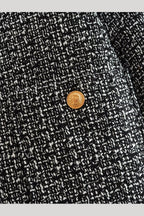 Cadence Grey tweed fabric close-up showing the textured weave and an engraved gold button on the pocket.