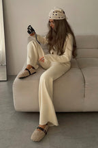 Camille Beige knit cardigan lounge set shown in a relaxed seated pose with a button-front cardigan and coordinated wide-leg pants