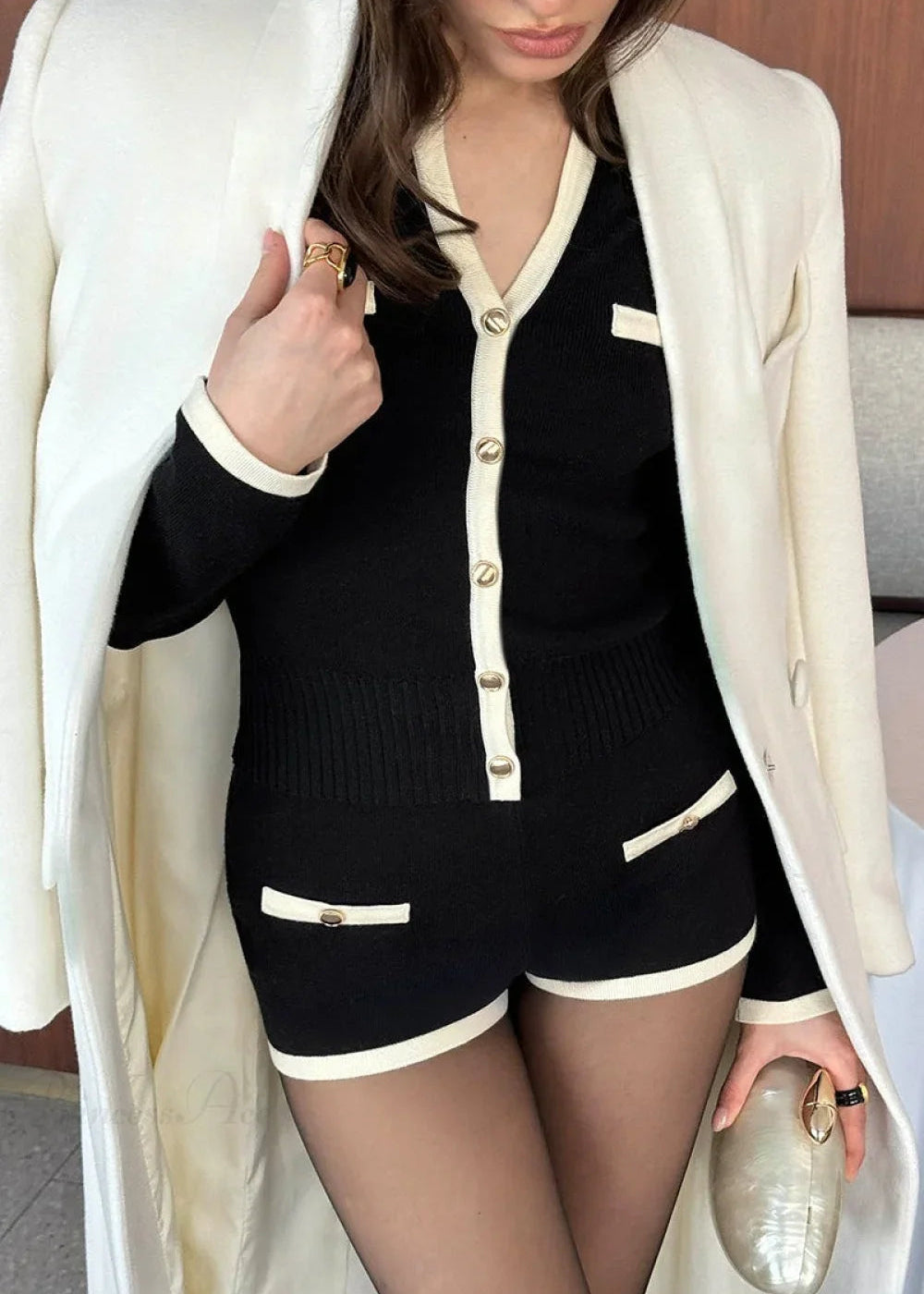 Camille Black knit set close-up showing the cream button placket, pocket accents, ribbed hem, and trimmed shorts.