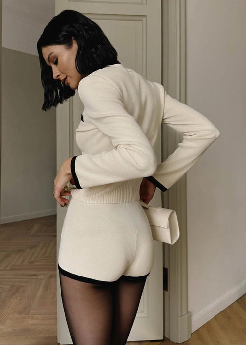 Camille White knit set shown from the back, with a ribbed cardigan hem, black cuff trim, and fitted shorts.