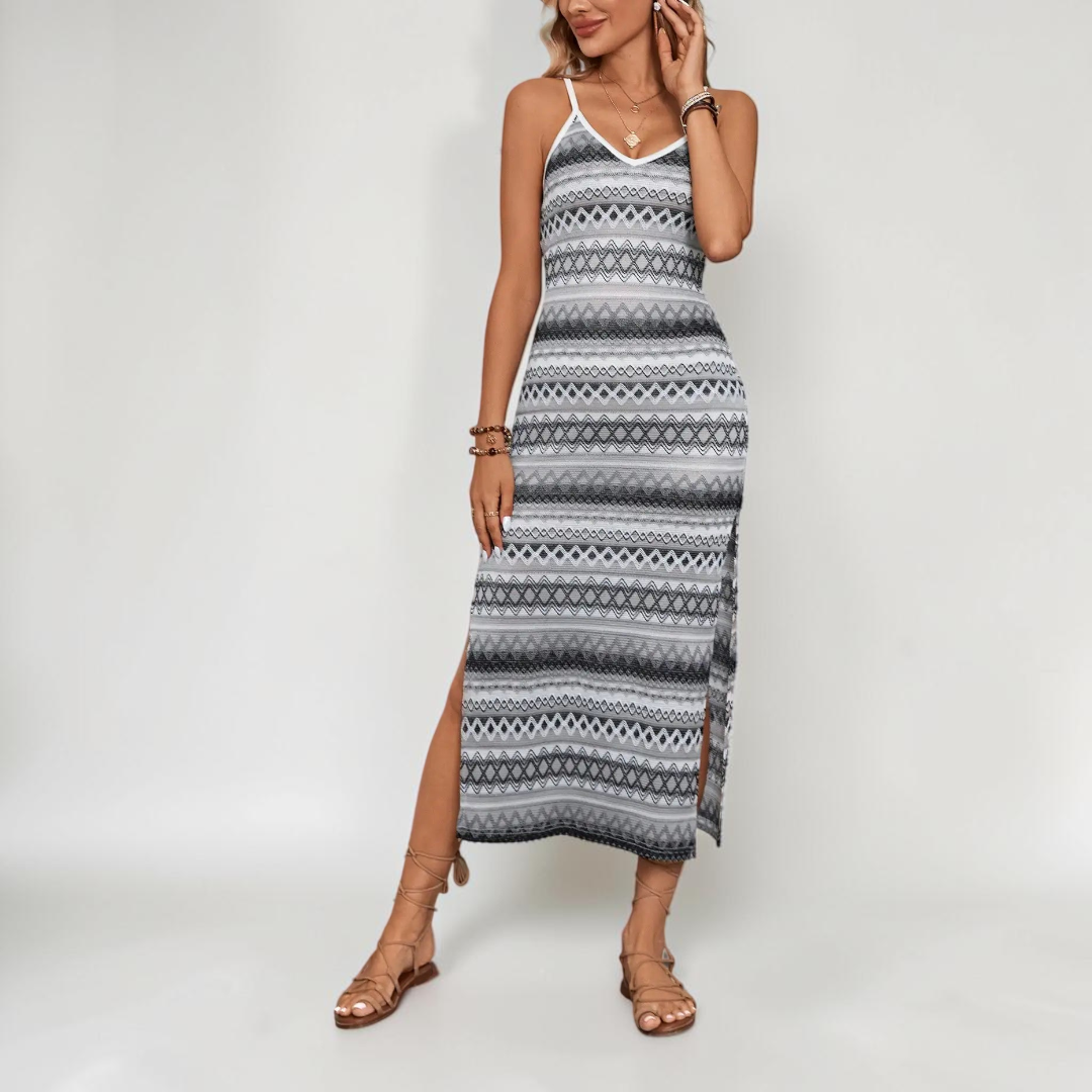 Lifestyle view of the Cassia Maxi Dress Knit Striped Cami Side-Slit in black, highlighting the sleeveless cami design, striped knit fabric, body-skimming fit, and side slit. Designed by Bella Hudson.