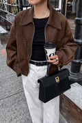 Celine Brown faux suede utility jacket worn open over a black tee with white pants and a black handbag.