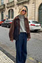 Celine Brown faux suede utility jacket worn zipped over a gray turtleneck with dark wide-leg jeans on the street.