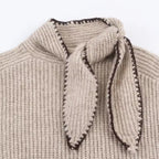 Close-up of Clara Khaki ribbed knit sweater showing the stand collar, decorative necktie, and textured knit fabric