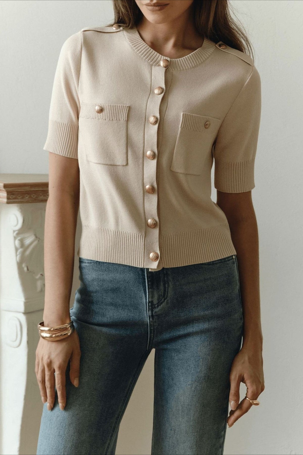 Clara Khaki knit cardigan shown from the front with gold buttons, ribbed trim, and two chest pockets over jeans.