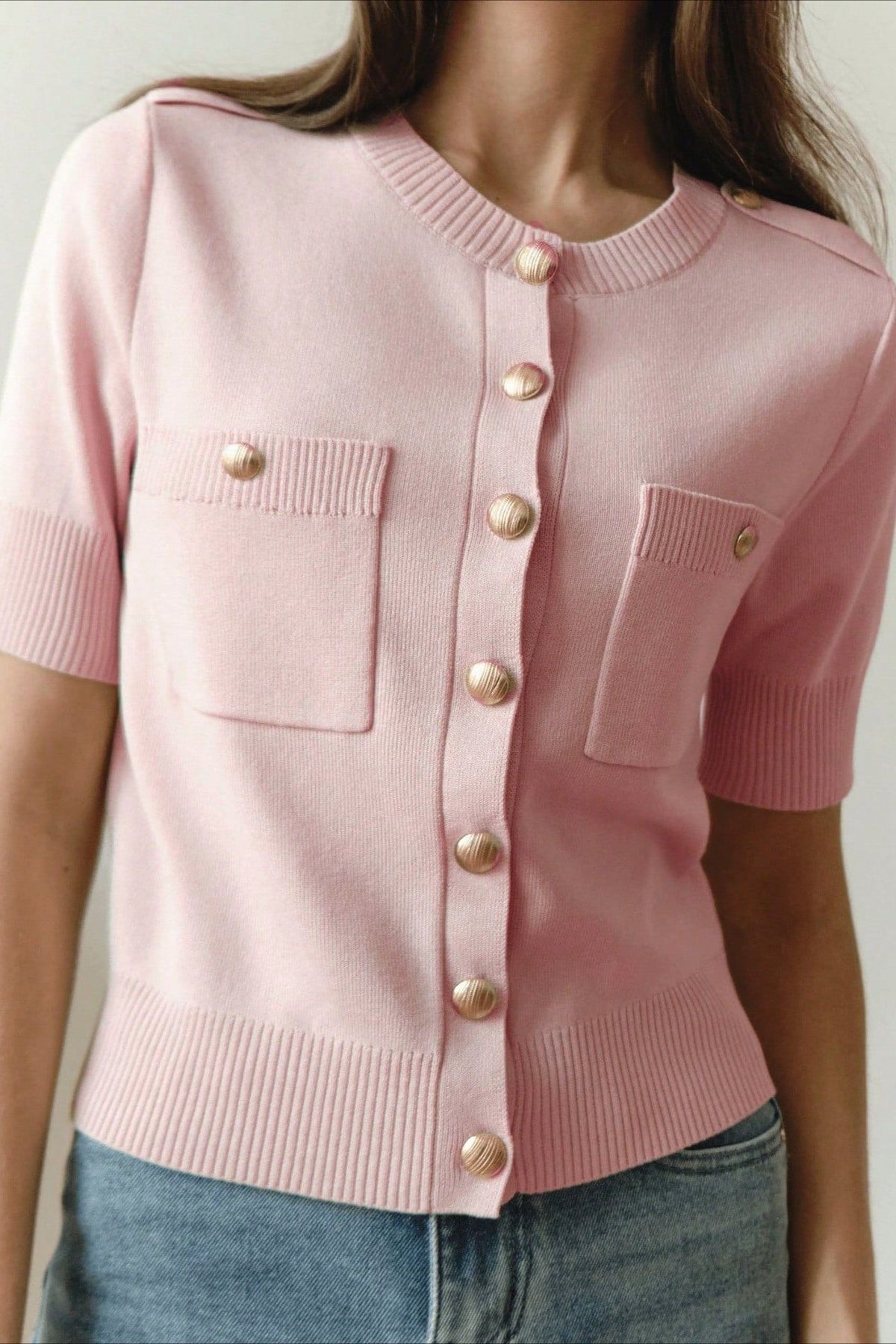 Clara Pink knit cardigan close-up showing gold buttons, ribbed cuffs, and patch pockets.