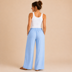 Back view of the Cleo Lightweight Linen Wide-Leg Summer Pants in blue, featuring a relaxed wide-leg silhouette and breathable linen fabric. Designed by Bella Hudson.