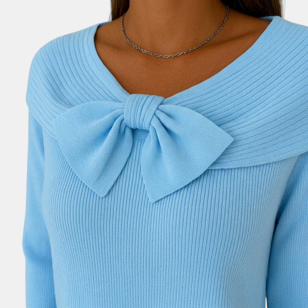 Close-up detail of the Colette Bow-Tie Long Sleeve T-shirt in blue, showcasing the decorative bow neckline, ribbed knit texture, and soft comfortable fabric. Designed by Bella Hudson.