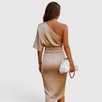 Back view of the Corinne Cocktail Dress Satin One-Shoulder Side-Slit in champagne, highlighting the asymmetrical one-shoulder design, elegant satin finish, and fitted silhouette. Designed by Bella Hudson.