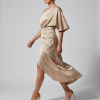 Side view of the Corinne Cocktail Dress Satin One-Shoulder Side-Slit in champagne, showcasing the one-shoulder neckline, flowing satin fabric, gathered waist, and flattering side slit. Designed by Bella Hudson.