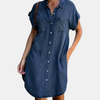 Front view of the Corinne Shirt Dress Chambray Denim Button-Front in dark blue, featuring a collared neckline, button-front closure, rolled cap sleeves, chest pockets, and a relaxed chambray silhouette. Designed by Bella Hudson.