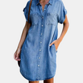 Front detail view of the Corinne Shirt Dress Chambray Denim Button-Front in light blue, showcasing the collared neckline, chest pockets, rolled cap sleeves, and relaxed shirt dress silhouette. Designed by Bella Hudson.