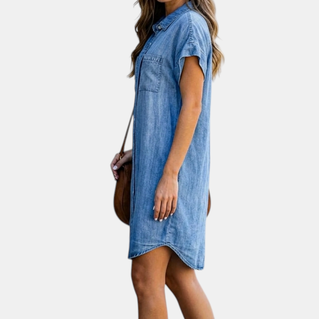 Side view of the Corinne Shirt Dress Chambray Denim Button-Front in light blue, showcasing the relaxed fit, rolled cap sleeves, collared neckline, and lightweight chambray fabric. Designed by Bella Hudson.