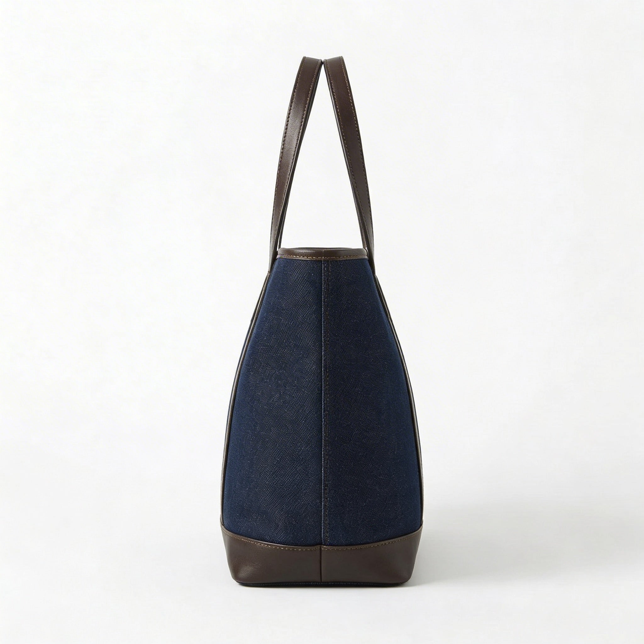 Side profile of dark blue denim tote bag with leather handles BELLA HUDSON