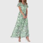 Front view of the Delphine Summer Maxi Dress Floral Print Flutter Sleeve in green, featuring flutter sleeves, a V-neckline, floral print, and a graceful flowing maxi-length design. Designed by Bella Hudson.