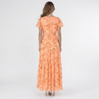Back view of the Delphine Summer Maxi Dress Floral Print Flutter Sleeve in orange, highlighting the flowing tiered skirt, flutter sleeves, and elegant floral pattern. Designed by Bella Hudson.