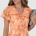 Close-up detail of the Delphine Summer Maxi Dress Floral Print Flutter Sleeve in orange, featuring the V-neckline, flutter sleeves, delicate floral print, and softly gathered bodice. Designed by Bella Hudson.