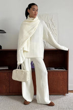Elena White cable-knit turtleneck sweater with wide-leg pants and a draped matching scarf, styled with a cream handbag.