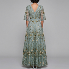 Back view of the Elodie Summer Maxi Dress Floral Print Wide Sleeve in green, highlighting the flowing floral skirt, flutter sleeves, and graceful full-length silhouette. Designed by Bella Hudson.