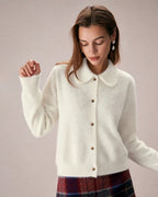 Elowen Apricot collared cardigan worn buttoned up over a plaid skirt, shown from the front with ribbed cuffs and brown buttons.