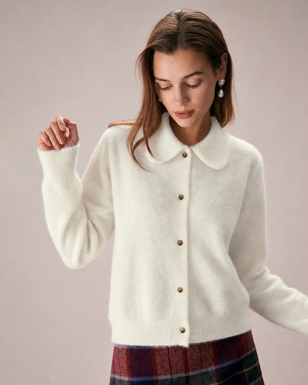 Elowen Apricot collared cardigan worn buttoned up over a plaid skirt, shown from the front with ribbed cuffs and brown buttons.
