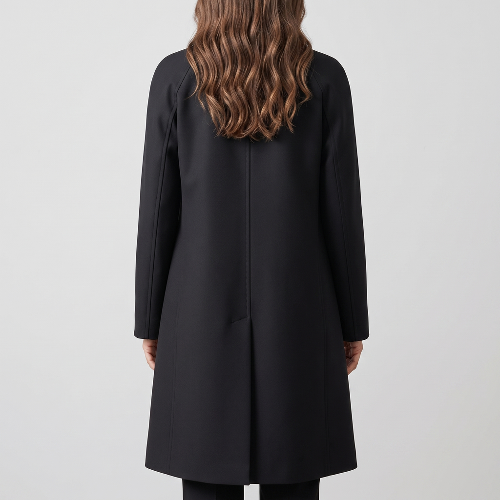 Back view of the Emilia Trench Coat Midi Double-Breasted in black, featuring a clean structured back, long sleeves, and a straight midi-length silhouette. Designed by Bella Hudson.