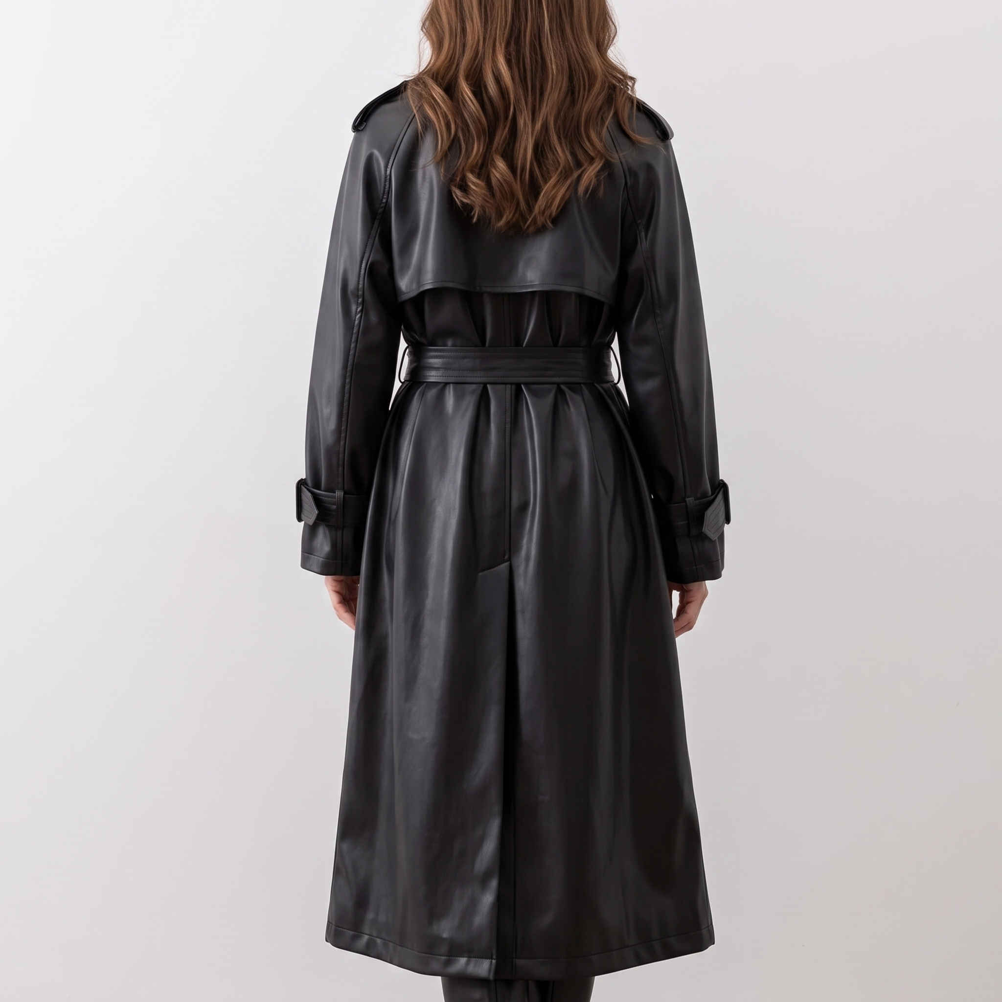 Back view of the Emma Trench Coat Faux-Leather Belted in black, featuring a tied waist belt, long sleeves, structured back construction, and knee-length silhouette. Designed by Bella Hudson.