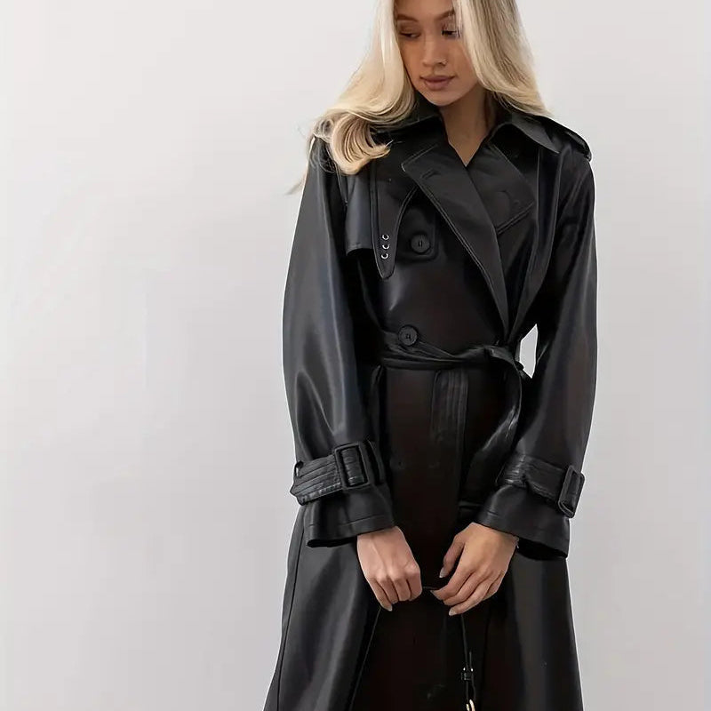 Full front view of the Emma Trench Coat Faux-Leather Belted in black, showcasing the wide lapel collar, double-breasted button closure, belted waist, long sleeves, and knee-length silhouette. Designed by Bella Hudson.