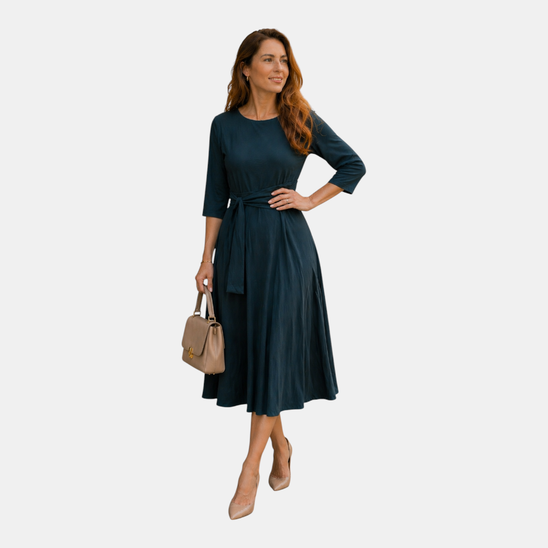 Posing view of the Estelle Midi Dress Cotton A-Line Tie-Waist in green, featuring a relaxed A-line silhouette, round neckline, self-tie waist, and elegant everyday styling. Designed by Bella Hudson.