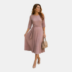 Twirling view of the Estelle Midi Dress Cotton A-Line Tie-Waist in pink, highlighting the flowing A-line skirt, self-tie waist, and graceful movement. Designed by Bella Hudson.