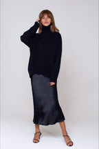 Evelyn Black turtleneck sweater styled with a satin midi skirt and strappy sandals in a full-length view.