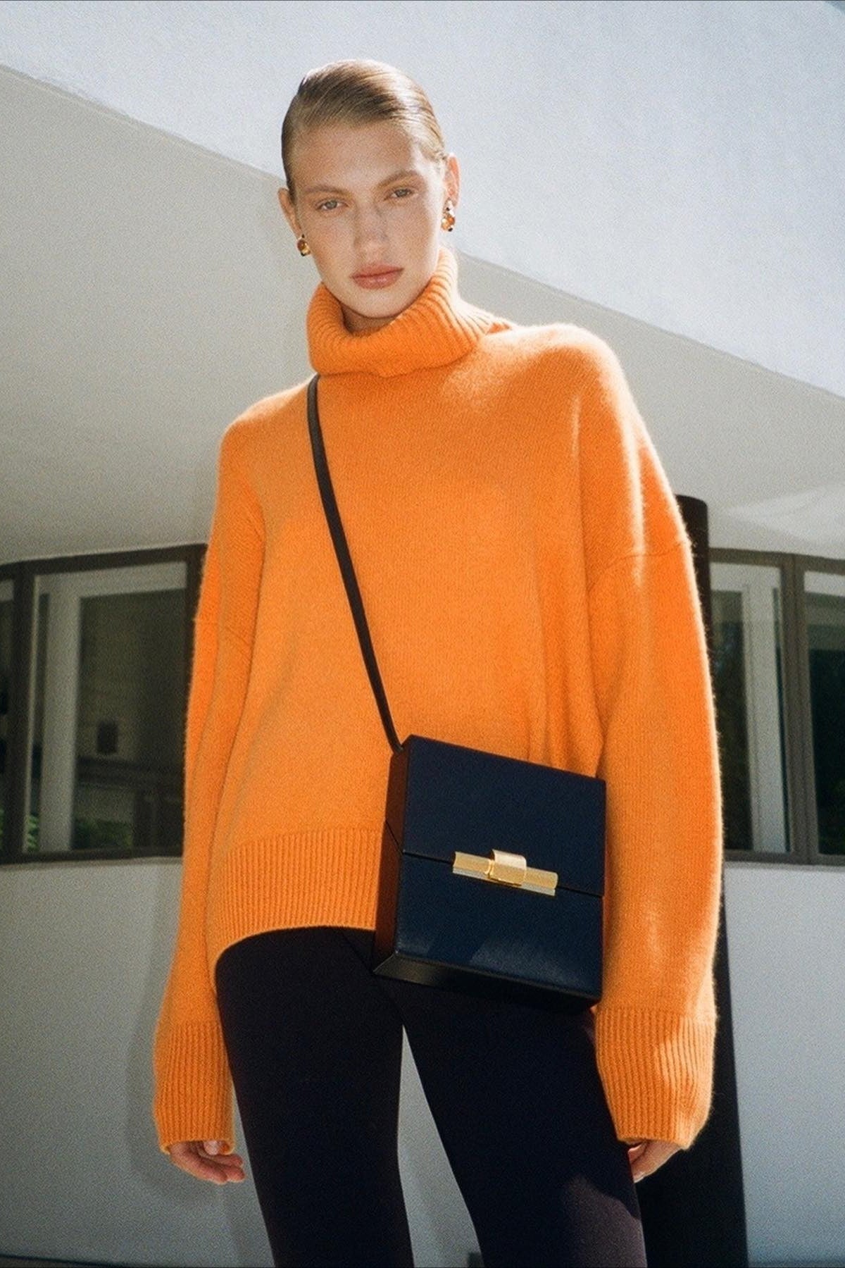 Evelyn Orange turtleneck sweater styled with black leggings, showing the oversized relaxed fit.