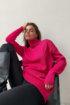 Evelyn Pink turtleneck sweater worn with black leggings and boots, showing the longer relaxed length and ribbed hem.