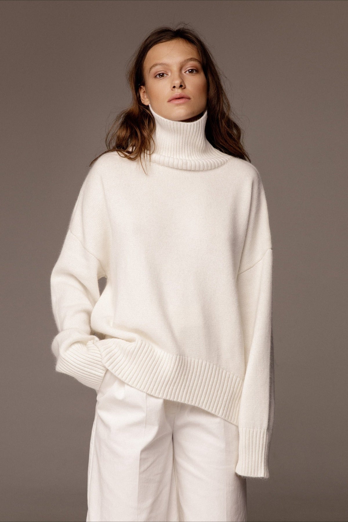 Evelyn White turtleneck sweater styled with white trousers, showing the relaxed fit and ribbed hem.