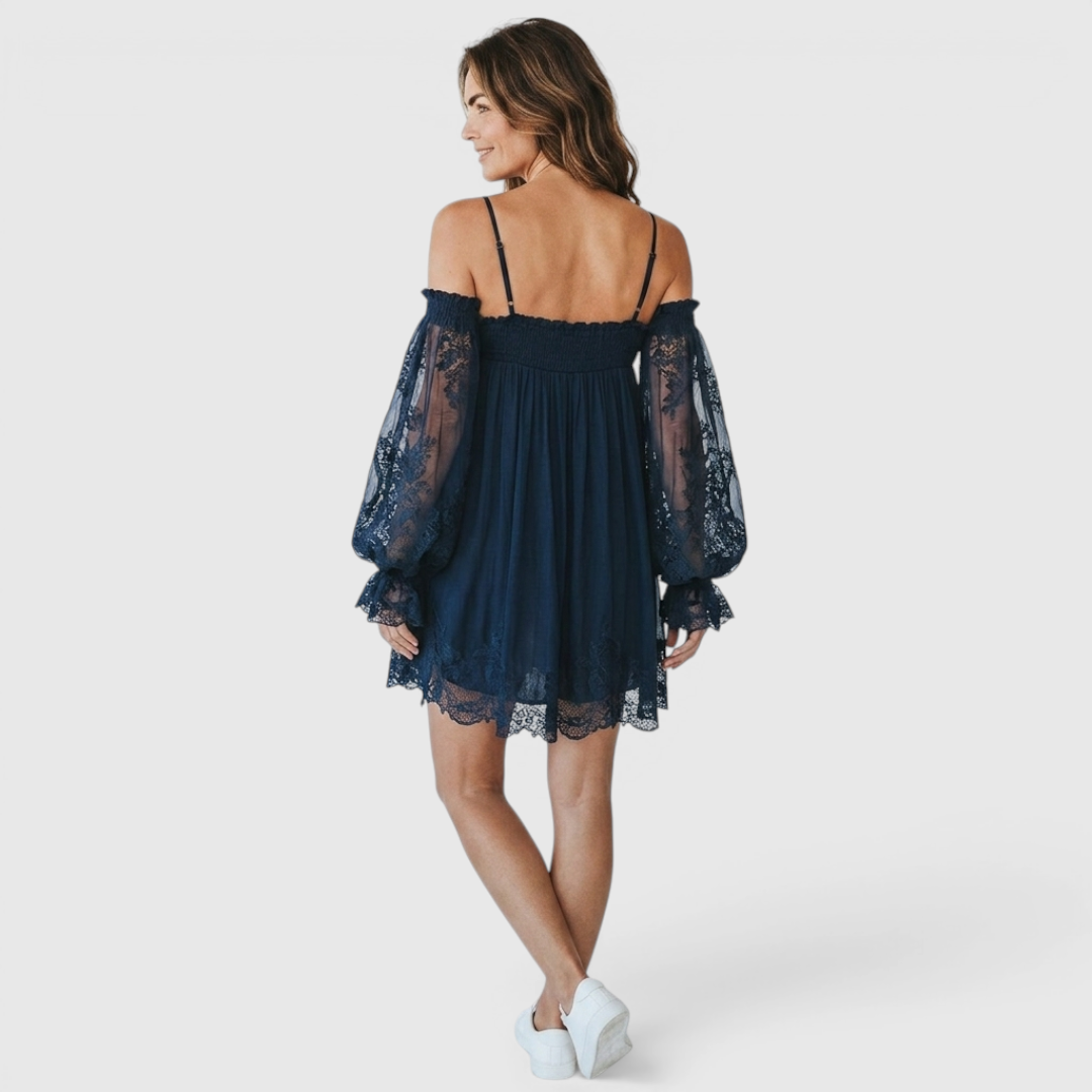 Back view of the Fenella Mini Dress Off-Shoulder Lace Puff-Sleeve Boho in navy blue, highlighting the off-the-shoulder back, sheer lace puff sleeves, and relaxed babydoll silhouette. Designed by Bella Hudson.