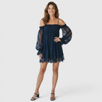 Front view of the Fenella Mini Dress Off-Shoulder Lace Puff-Sleeve Boho in navy blue, featuring an off-the-shoulder neckline, sheer lace puff sleeves, a relaxed babydoll silhouette, and a scalloped lace hem. Designed by Bella Hudson.
