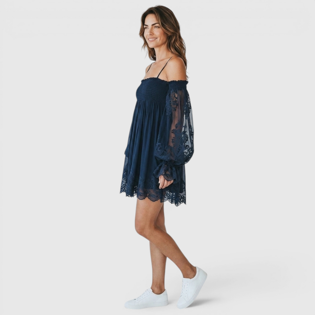 Side view of the Fenella Mini Dress Off-Shoulder Lace Puff-Sleeve Boho in navy blue, showcasing the off-the-shoulder neckline, voluminous lace sleeves, and flowing mini-length silhouette. Designed by Bella Hudson.