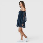 Side view of the Fenella Mini Dress Off-Shoulder Lace Puff-Sleeve Boho in navy blue, showcasing the off-the-shoulder neckline, voluminous lace sleeves, and flowing mini-length silhouette. Designed by Bella Hudson.