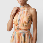 Close-up detail of the Fenna Maxi Lightweight Dress Watercolor-Print Halter in peach, featuring the halter neckline, gathered bodice, watercolor floral print, and lightweight flowing fabric. Designed by Bella Hudson.