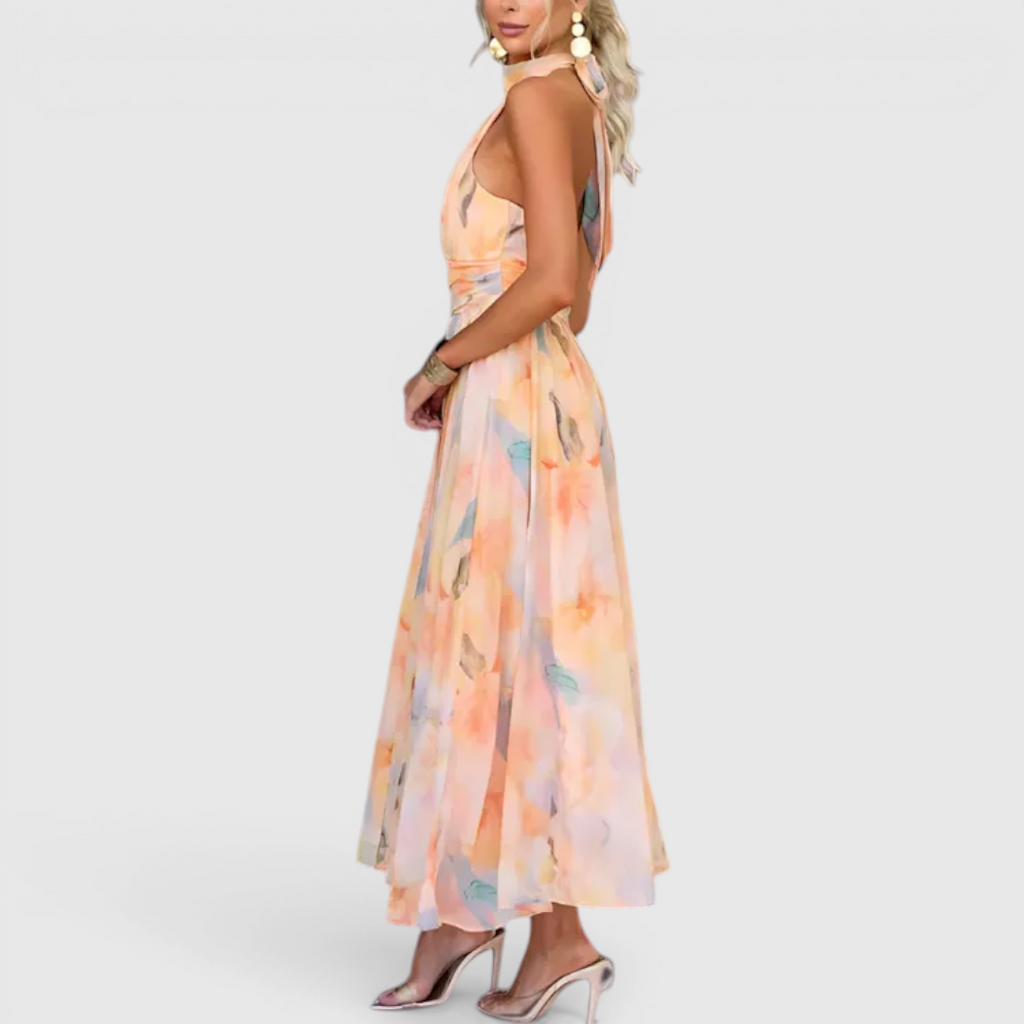 Side view of the Fenna Maxi Lightweight Dress Watercolor-Print Halter in peach, showcasing the halter neckline, sleeveless silhouette, lightweight flowing fabric, and soft watercolor floral print. Designed by Bella Hudson.