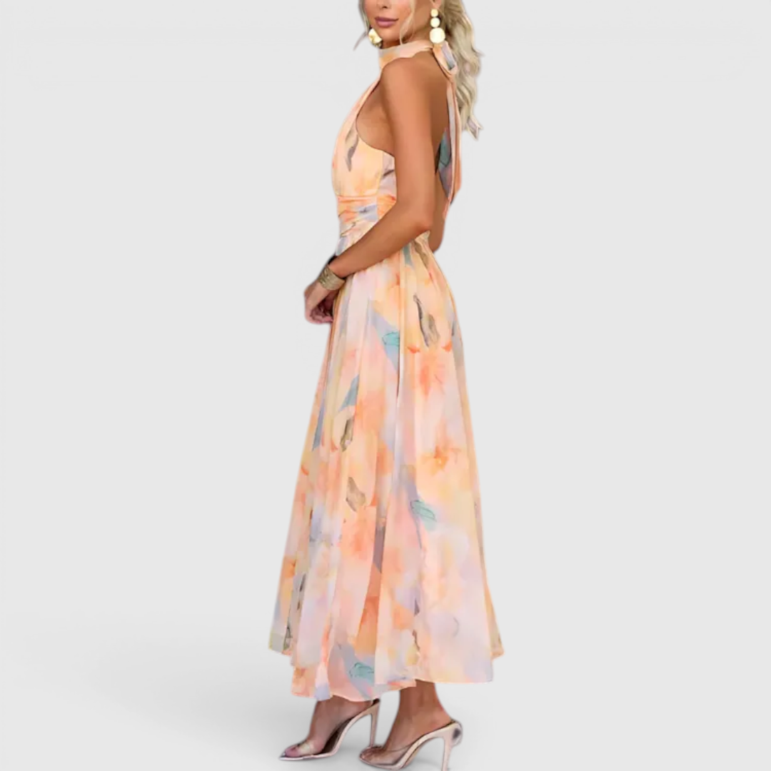 Side view of the Fenna Maxi Lightweight Dress Watercolor-Print Halter in peach, showcasing the halter neckline, sleeveless silhouette, lightweight flowing fabric, and soft watercolor floral print. Designed by Bella Hudson.