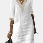 Front view of the Fenna Shift Dress Cotton Crochet-Trim V-Neck in white, featuring a crochet-trim V-neckline, rolled three-quarter sleeves, side pockets, and a relaxed shift silhouette. Designed by Bella Hudson.