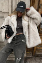 Fiora White faux fur jacket worn open with a wide lapel collar over a fitted top and distressed gray jeans.