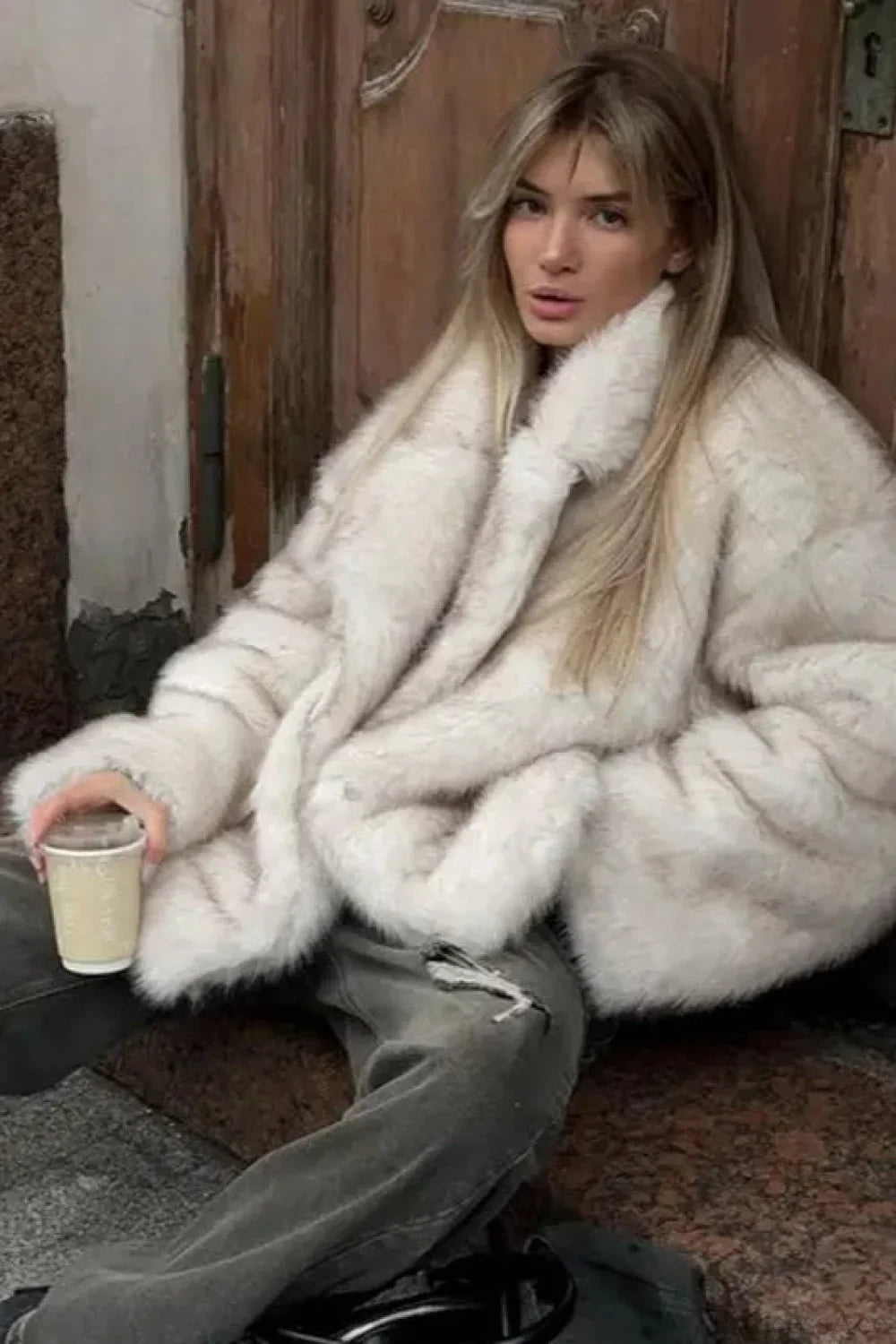 Fiora White faux fur jacket in a seated styled shot showing the plush texture and oversized shape.