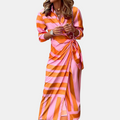 Front view of the Freya Summer Midi Dress Striped Wrap in orange, featuring a collared neckline, long sleeves, wrap-style waist tie, bold striped pattern, and a flowing midi-length silhouette. Designed by Bella Hudson.
