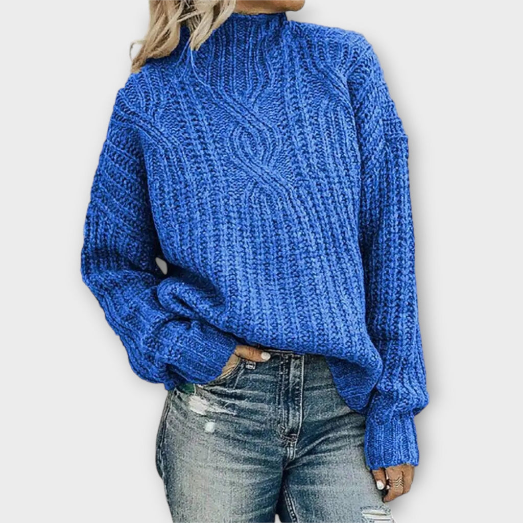 Front view of the Halvard Sweater Cable-Knit Turtleneck in blue, featuring a high turtleneck, textured cable-knit pattern, long sleeves, and a relaxed cozy silhouette. Designed by Bella Hudson.