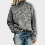 Front view of the Halvard Sweater Cable-Knit Turtleneck in gray, featuring a high turtleneck, textured cable-knit pattern, long sleeves, and a relaxed silhouette. Designed by Bella Hudson.