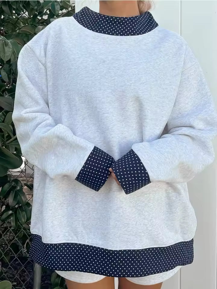 Hazel Blue oversized crewneck sweatshirt with contrasting polka-dot neckline, long sleeves, patterned cuffs, and hem detailing