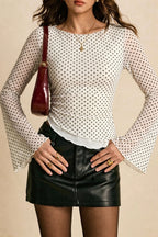 Isla White Small Dot mesh top styled with a mini skirt and shoulder bag, showing the round neckline and flared cuffs.